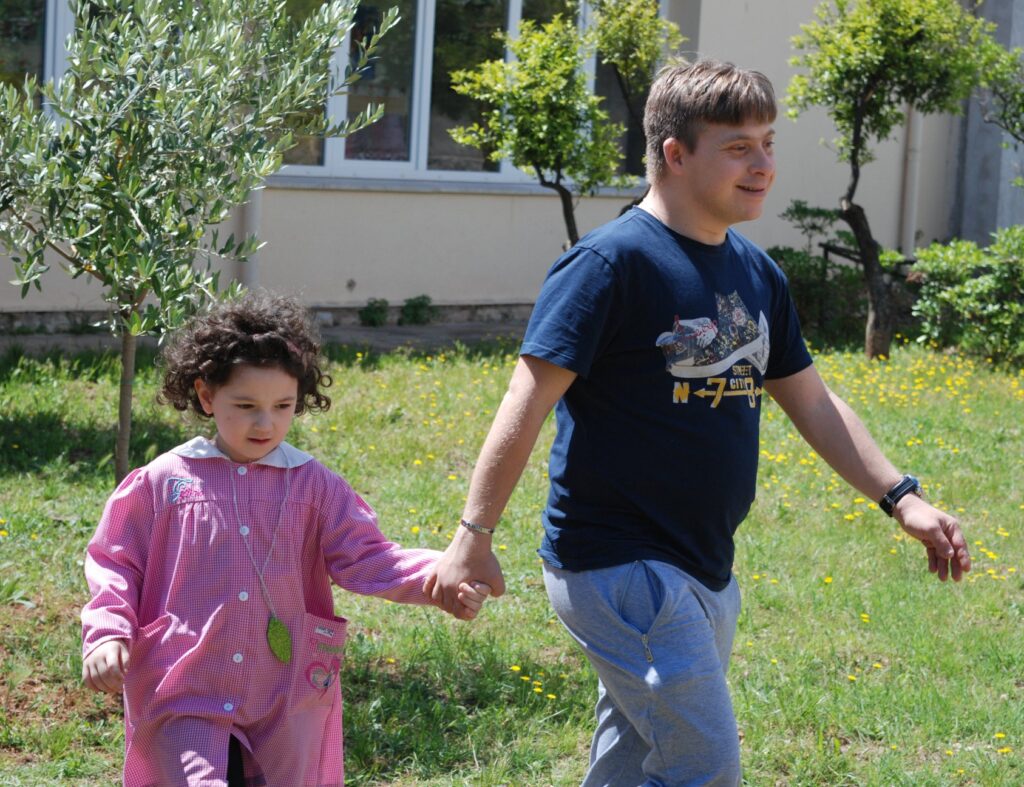 Dieses Bild dient nur als ein Symbol für das Thema Ehrenamt. Klicken Sie darauf, wenn Sie zum Menüpunkt Ehrenamt springen möchten. Auf dem Bild sind zwei Kinder in einem Garten zu sehen. Ein Junge hält ein kleineres Mädchen an der Hand und hilft ihr.